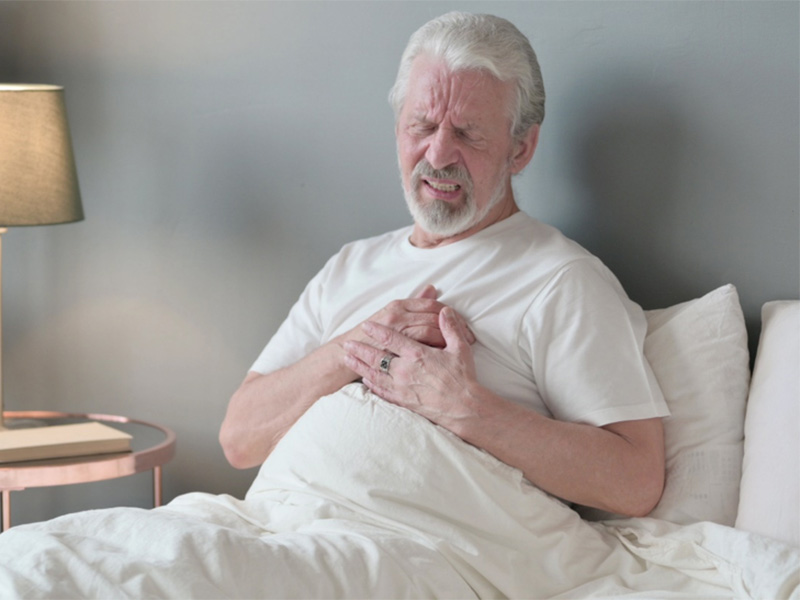 Person sitting in bed holding chest