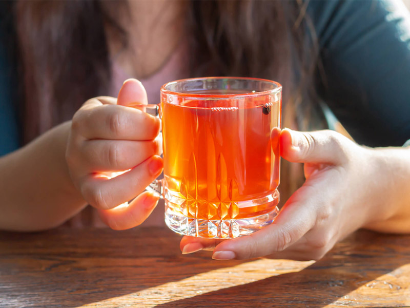 Hand holding a glass cup of tea