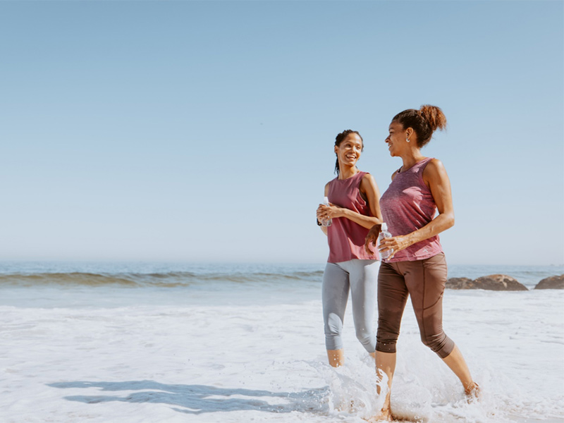 Two people walking in shallow water at beach